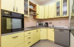 a kitchen with yellow cabinets and a black appliance at Vallelosca Garden in Opatija