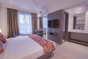 a hotel room with a bed and a television at Hotel Park Tree, Kolhapur in Kolhapur