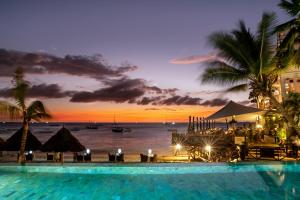 a pool with a view of the ocean at sunset at Z Hotel in Nungwi