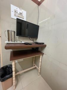 einen Schreibtisch mit einem Computermonitor darüber in der Unterkunft Golden Guest House in Bangalore