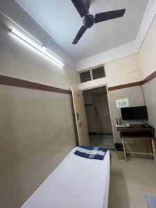 Zimmer mit einem Bett, einem Schreibtisch und einem Deckenventilator. in der Unterkunft Golden Guest House in Bangalore