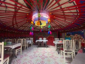 a dining room with tables and chairs and a large ceiling at Naryn Guest House in Naryn