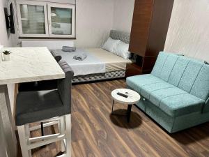 a small room with a bed and a blue couch at Pink House Apartments in Jagodina