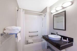 a bathroom with a sink and a toilet and a tub at Days Inn by Wyndham Ennis in Ennis
