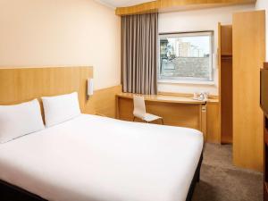 a hotel room with a bed and a desk and a window at ibis Nottingham Centre in Nottingham