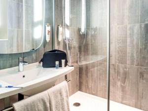 een badkamer met een douche, een wastafel en een spiegel bij ibis Paris Bercy Village in Parijs