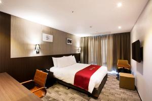 a hotel room with a bed and a desk at Ramada by Wyndham Jeju City Hall in Jeju