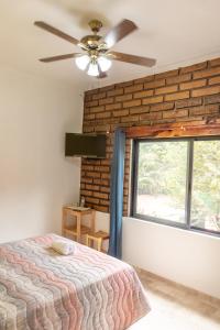 een slaapkamer met een bakstenen muur, een bed en een plafondventilator bij CASA ANTARES in Tepoztlán