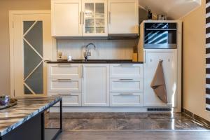 a kitchen with white cabinets and a sink at Deluxe Apartment mit Tiefgarage in Nähe Messe-BMW-Porsche-DHL-Flughafen-Flugzeugwerk der Deutsche Aircraft in Leipzig