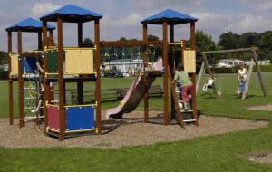 um parque infantil com escorrega e pessoas a brincar nele em Lakes and woodlands Overstone Holiday Park em Northampton