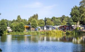 a group of houses next to a lake at Lakes and woodlands Overstone Holiday Park in Northampton