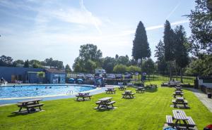 a pool with picnic tables in a grass field at Lakes and woodlands Overstone Holiday Park in Northampton