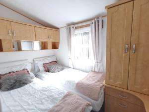 1 dormitorio con 2 camas y ventana en Lakes and woodlands Overstone Holiday Park, en Northampton