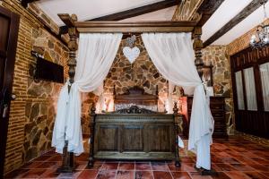 1 dormitorio con cama de madera en una pared de piedra en Hotel Rural Finca La Herencia en Guadalcanal