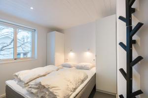 a bedroom with a bed with white sheets and a window at Bruksvallarna - Modern fjällstuga med panoramautsikt och WiFi in Bruksvallarna
