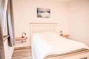 a white bedroom with a bed and two lamps at Ferienwohnung Bad Vilbel in Bad Vilbel