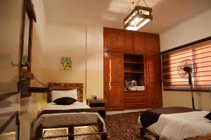 a bedroom with two beds and a dresser in it at Petra Wooden House in Wadi Musa