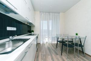 a kitchen with a sink and a table with chairs at Видовая на 25 этаже in Kyiv