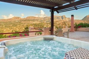 un patio con bañera de hidromasaje y vistas a las montañas en Mouri Villa, en Mouríon