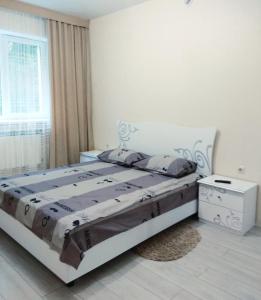a white bedroom with a bed and a window at Apartments near Dolphinarium in Truskavets