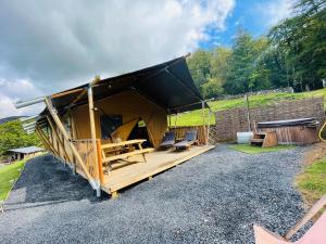 a tent with a black roof on a gravel road at Mountain View Safari Tent with Hot Tub in The Heart of Snowdonia in Dolgellau