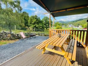 a wooden deck with a bench and a table at Mountain View Safari Tent with Hot Tub in The Heart of Snowdonia in Dolgellau