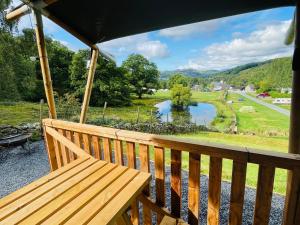 a wooden bench on a porch with a view of a lake at Mountain View Safari Tent with Hot Tub in The Heart of Snowdonia in Dolgellau