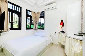 Dormitorio blanco con cama y ventanas en Blue Lagoon Apartment 3br, en Kuta