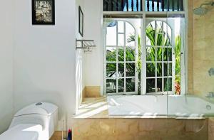 baño con bañera y ventana grande en Blue Lagoon Apartment 3br, en Kuta