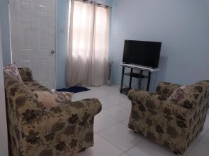 uma sala de estar com 2 cadeiras e uma televisão de ecrã plano em Avocado Suites em Castries