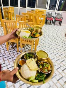 a person holding a tray of food on a table at Himchuli Guest House in Bandipur