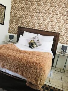 una camera da letto con un letto con una coperta marrone e cuscini di Dwengu Guest house a Margate