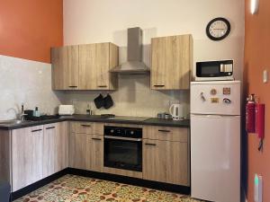een keuken met houten kasten en een witte koelkast bij Parisio One Bedroom Maisonette in Sliema in Sliema
