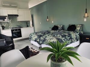 a bedroom with a bed and a table with a plant at Sea-esta in Plettenberg Bay