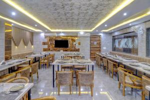 a dining room with tables and chairs and a tv at Hotel Anand Villa in Agra