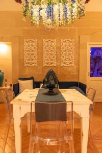una sala da pranzo con tavolo, sedie e lampadario pendente di Cadelli Luxury Suite & Apartments a Lecce