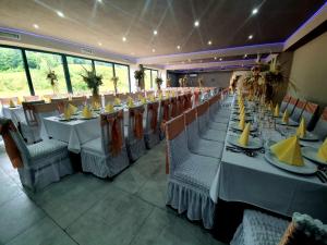 une grande salle à manger avec des tables et des chaises blanches dans l'établissement MOTEL ALADIN, à Cazin