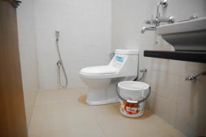 een badkamer met een toilet, een wastafel en een emmer bij Harekrishna Hotel & Restaurant in Bhubaneshwar
