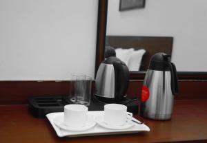 a coffee maker and two cups on a table at Harekrishna Hotel & Restaurant in Bhubaneshwar