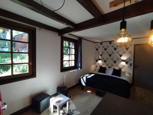 a bedroom with a bed and two windows at Chalet Appart'Hôtel l'Eau Vive in Saint-Nicolas-la-Chapelle
