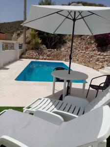 a table and chairs with an umbrella next to a pool at Almond Reef Casa Rural in Los Alias