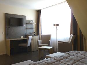 Habitación de hotel con cama, escritorio y TV. en Hotel Jellentrup en Münster