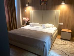 um quarto com uma cama grande com lençóis brancos e almofadas em Lotus Hotel Chisinau em Chişinău