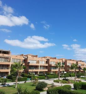 a large apartment building with palm trees in a park at Chalet duplex in El Alamein