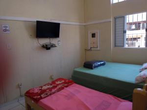 a room with two beds and a flat screen tv at Casa de hospedagem in Aparecida