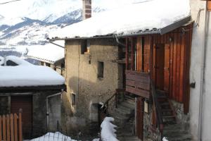 a building with snow on the roof and a staircase at La Marguerite in Aigueblanche