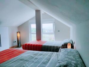 two beds in a room with a window at La Ola de Cantabria in Miengo