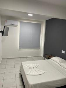 une chambre avec un lit blanc avec une fenêtre dans l'établissement Bravo City Hotel São Jose do Rio Preto Ltda, à Sao Jose do Rio Preto