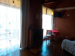 a living room with a fireplace and a table and window at Chalé Recanto do Sol in Paraisópolis