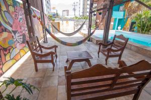 Salve Maloca Hostel في فورتاليزا: فناء مع كراسي وأرجوحة وطاولة